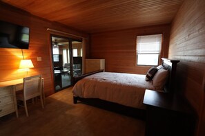 Een slaapkamer met een bed, een bureau, een stoel, een televisie en een raam.