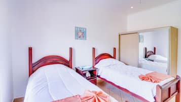 A hotel room with two single beds, a nightstand, a mirror, and a wall decoration.