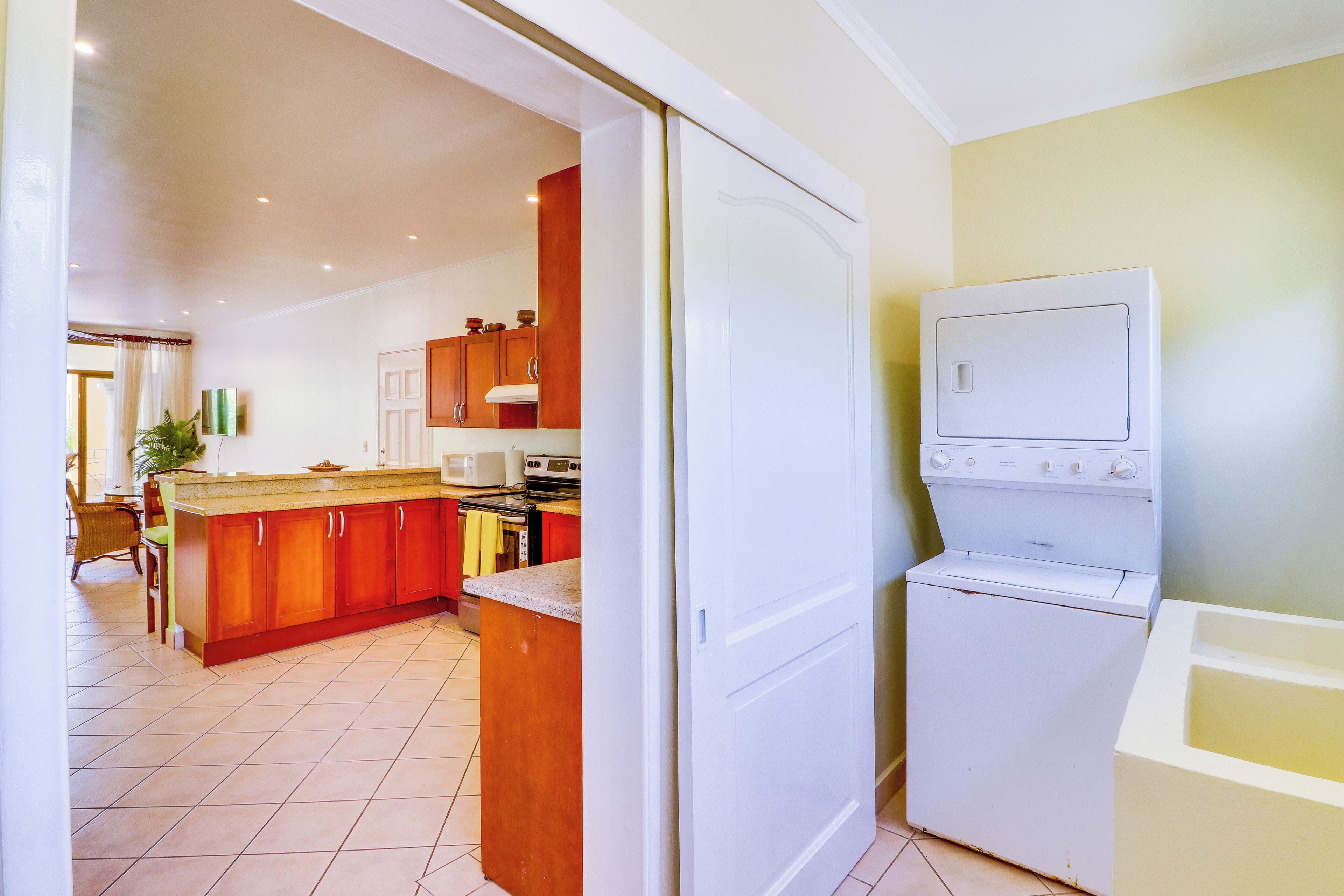 A kitchen with wooden cabinets, a microwave, an oven, and a washing machine.