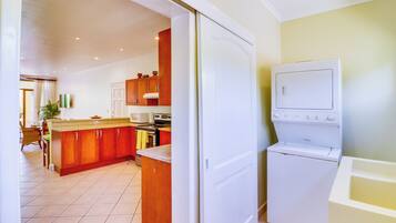 A kitchen with wooden cabinets, a microwave, an oven, and a washing machine.