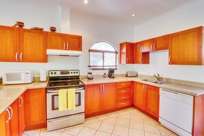 Una cocina con armarios de madera, estufa, microondas y lavavajillas.