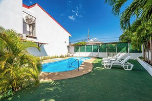 A swimming pool with a clear blue water, surrounded by artificial grass and white lounge chairs. - Playas del Coco Condo w/ Pool: Walk to Beach! (Playas del Coco)