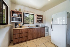 A kitchen with wooden cabinets, a microwave, a stove, and a refrigerator. - Playas del Coco Condo w/ Pool: Walk to Beach! (Playas del Coco)