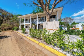 A two-story building with a balcony, surrounded by greenery and a gravel path. - Playas del Coco Condo w/ Pool: Walk to Beach! (Playas del Coco)