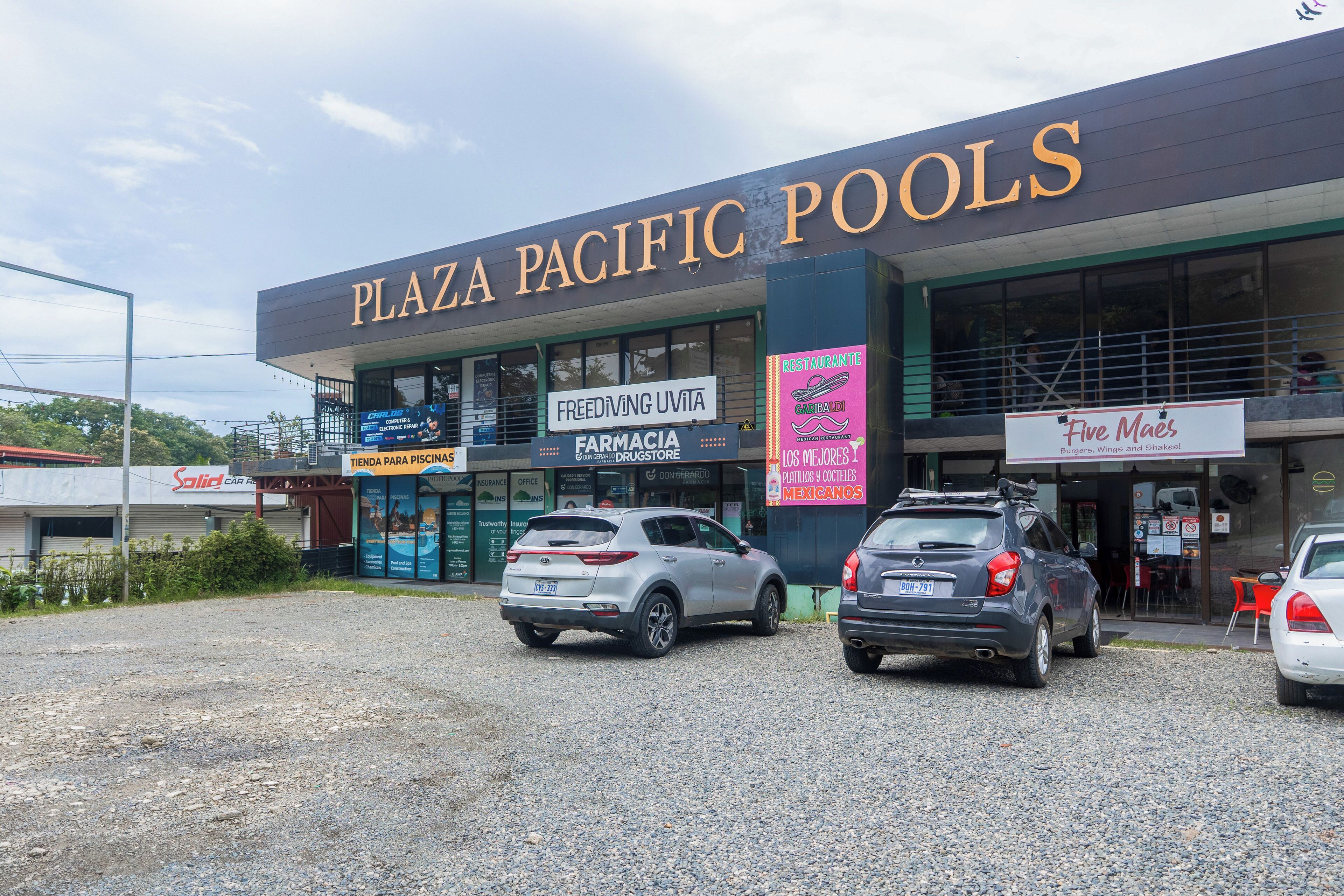 A commercial building with multiple businesses including a pool center, pharmacy, and a restaurant.