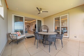 An open-plan living area with a dining table and chairs, a sofa, and a ceiling fan. - Tamarindo Ocean-View Condo, Shared Infinity Pool (Tamarindo)