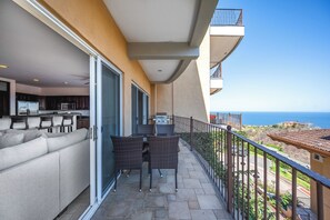 Een balkon met een eethoek, een keuken en uitzicht op zee.