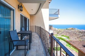 A balcony with a table and chairs, a view of the sea, and a building with a balcony. - Relaxing 3BR Ocean-View Condo | 2 Balconies (Playas del Coco)