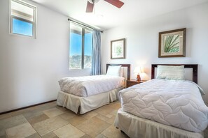 A hotel room with two beds, a ceiling fan, a window with curtains, and framed botanical prints on the wall. - Relaxing 3BR Ocean-View Condo | 2 Balconies (Playas del Coco)