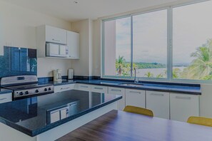 Een moderne keuken met een groot eiland, een magnetron en een koffiezetapparaat.