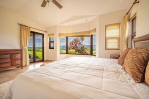 A bedroom with a large bed, a wooden dresser, and a view of the outdoors through a sliding glass door. - Stunning Lake Arenal Views: Duplex Unit w/ Patio! (La Fortuna)