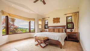Quarto com cama grande, mesa de cabeceira, cadeira e vista para o exterior.