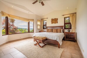 A bedroom with a large bed, a nightstand, a chair, and a view of the outdoors. - Stunning Lake Arenal Views: Duplex Unit w/ Patio! (La Fortuna)