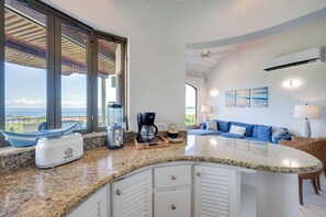 A kitchen with a granite countertop, a coffee maker, and a view of the ocean through large windows. - Walk to the Beach & Town! Tamarindo Condo (Tamarindo)