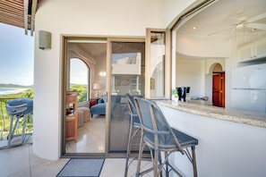 A modern kitchen with a built-in refrigerator, a dining area with a glass partition, and a view of the outdoors. - Walk to the Beach & Town! Tamarindo Condo (Tamarindo)