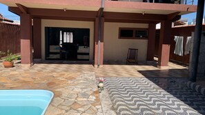 Un'area esterna coperta con piscina, pavimento in pietra e una sedia.