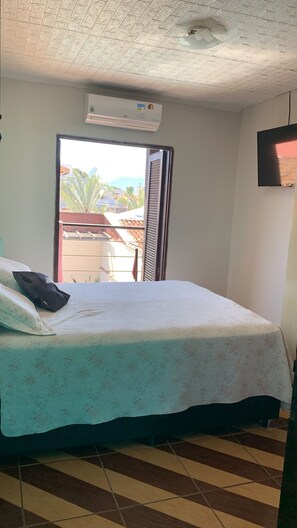 Una stanza con un letto, una finestra, un condizionatore d'aria e una televisione.