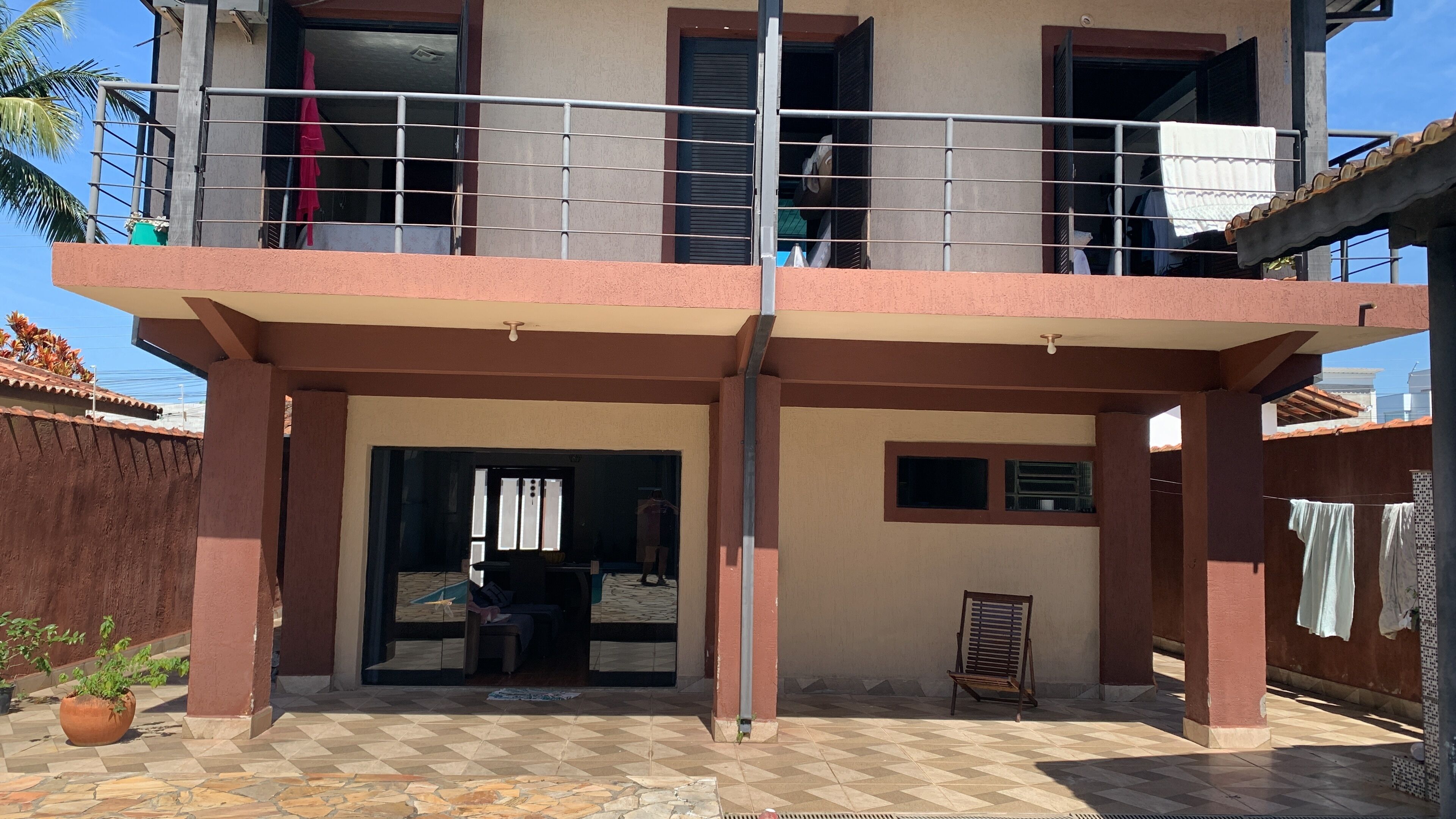 A two-story building with a balcony, a covered entrance, and a tiled patio area.