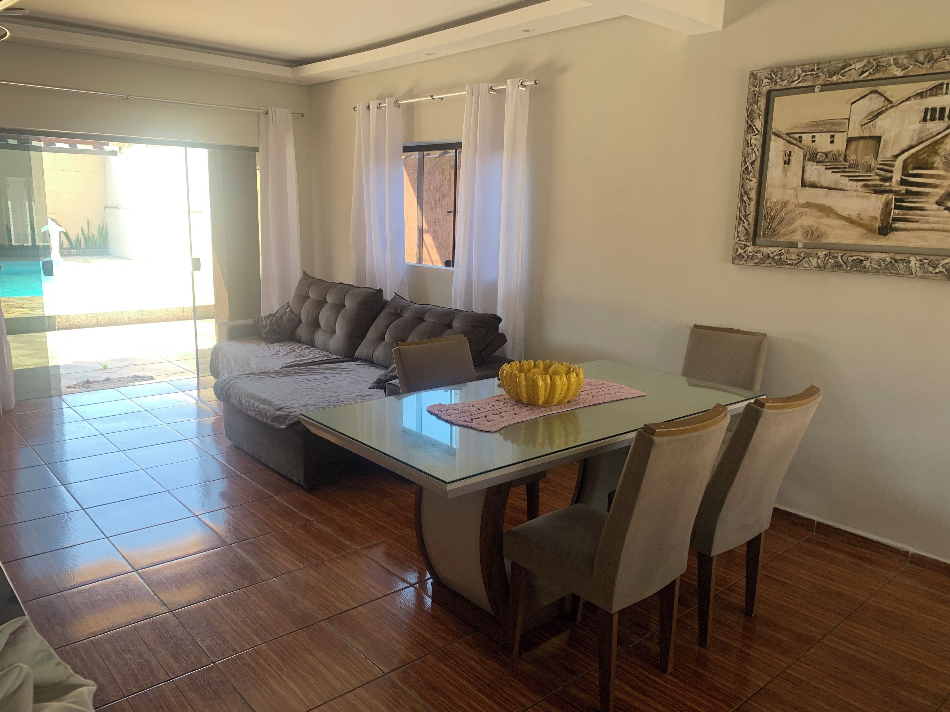 Una sala de estar moderna con una mesa de comedor de vidrio, un sofá con cojines y un cuadro en la pared.