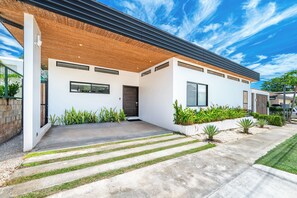 A modern house with a flat roof, large windows, and a concrete driveway. - Walk to Beach! Tamarindo Home w/ Private Pool (Tamarindo)