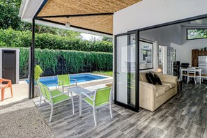 A modern outdoor living space with a pool, seating area, and a glass door leading to a kitchen. - Pool & Entertaining Patio: Playa Carrillo Home (Playa Carrillo)