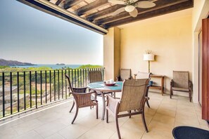 A balcony with a table and chairs, a lamp, and a view of the sea. - Playa Hermosa Penthouse: Ocean Views, 2 Pools (Playa Hermosa)