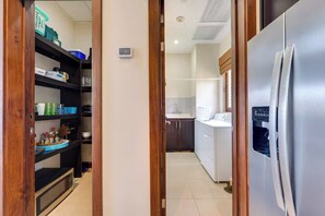 A narrow hallway with a kitchen area on the right, featuring a stainless steel refrigerator and a washing machine. - Playa Hermosa Penthouse: Ocean Views, 2 Pools (Playa Hermosa)
