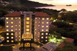 A multi-story hotel with a central atrium and a parking area. - Playa Hermosa Penthouse: Ocean Views, 2 Pools (Playa Hermosa)