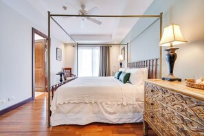 A four-poster bed with a canopy, a wooden nightstand with a lamp, and a view of the hallway. - Playa Hermosa Penthouse: Ocean Views, 2 Pools (Playa Hermosa)