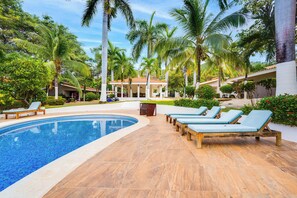 A pool area with lounge chairs and a covered seating area surrounded by palm trees. - 3-Unit Bundle: Club Voca Pool Access, Near Beach! (Playas del Coco)