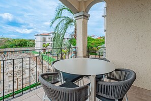 A balcony with a round table and two chairs, overlooking a construction site and a residential area. - 3 Mi to Beach: Modern Santa Cruz 2BR Condo (Tamarindo)