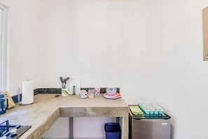 A kitchen with a countertop, a stove, a trash bin, and a refrigerator.