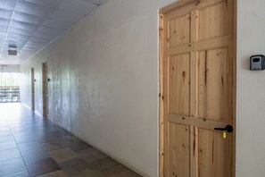 Ein Flur mit einer Holztür, einem Klingelknopf und einer wandmontierten Vorrichtung.