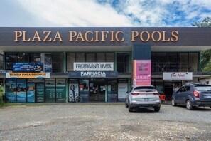 Ein Gebäude mit mehreren Geschäftsfassaden, darunter 'PLAZA PACIFIC POOLS' und 'FREEDIVING UVITA'.