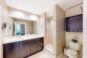 Een moderne badkamer met een wastafelmeubel met dubbele wastafel, een inloopdouche en een toilet.