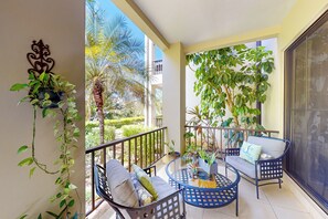 A balcony with a seating area, a potted plant, and a view of the surrounding greenery. - Playas del Coco: Balcony, Near Beaches! (Playas del Coco)