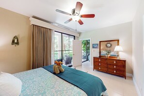 Een hotelkamer met een bed, een dressoir, een plafondventilator en uitzicht op de omgeving.