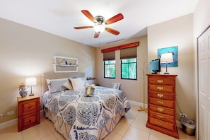 A bedroom with a bed, a nightstand, a dresser, a ceiling fan, a window with blinds, and a wall-mounted TV. - Playas del Coco: Balcony, Near Beaches! (Playas del Coco)