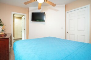 Ein Schlafzimmer mit einem Bett, einem an der Wand montierten Fernseher und einem Deckenventilator.
