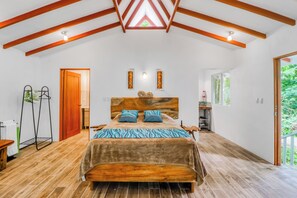 A bedroom with a wooden bed, a sloped ceiling, and a view of the outdoors. - Secluded Ojochal Studio w/ Trails & Pool Access! (Tres Rios)