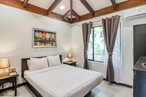 A hotel room with a bed, nightstands, a painting, a window with curtains, and an air conditioning unit. - Pool & Beach Access: 2-Unit Base in Playa Hermana (Playa Hermosa)