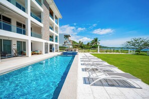 A modern hotel with a swimming pool, outdoor seating, and a view of the ocean. - Playa Potrero: 2 Balconies & Private Grill (Playa Potrero)