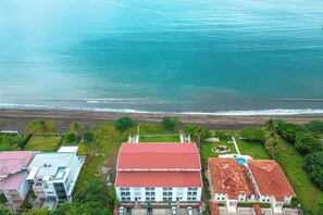 A coastal property with a red-roofed building, a swimming pool, and a beach view. - Oceanfront Escape in Playa Potrero, Costa Rica (Playa Potrero)