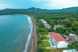 A coastal hotel with a beachfront view, a swimming pool, and a road leading to the beach. - Oceanfront Escape in Playa Potrero, Costa Rica (Playa Potrero)