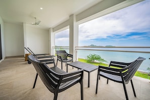 A balcony with a table and chairs, overlooking a body of water and distant land. - Oceanfront Escape in Playa Potrero, Costa Rica (Playa Potrero)