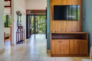 Ein Flur mit einem Holzschrank, einem an der Wand befestigten Fernseher und einem Bett im Hintergrund.