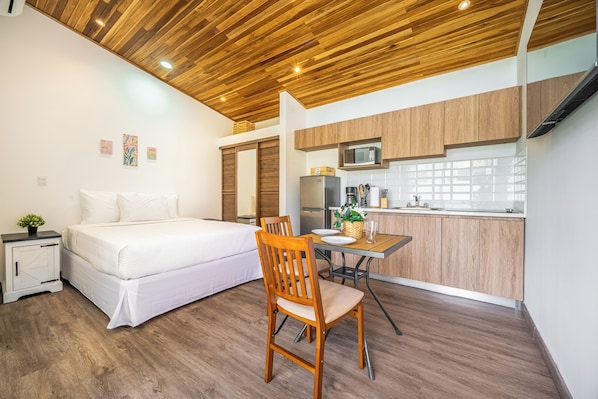 A compact bedroom with a bed, bedside table, and a small potted plant. Adjacent is a kitchenette with a microwave, sink, and cabinets. A dining area with a table and chair is also visible. - 2 Studios w/ Pool Access < 1 Mi to Playas Del Coco (Playas del Coco)