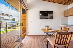 A modern kitchen with a flat-screen TV, wooden flooring, and a dining area with a table and chairs. - 2 Studios w/ Pool Access < 1 Mi to Playas Del Coco (Playas del Coco)