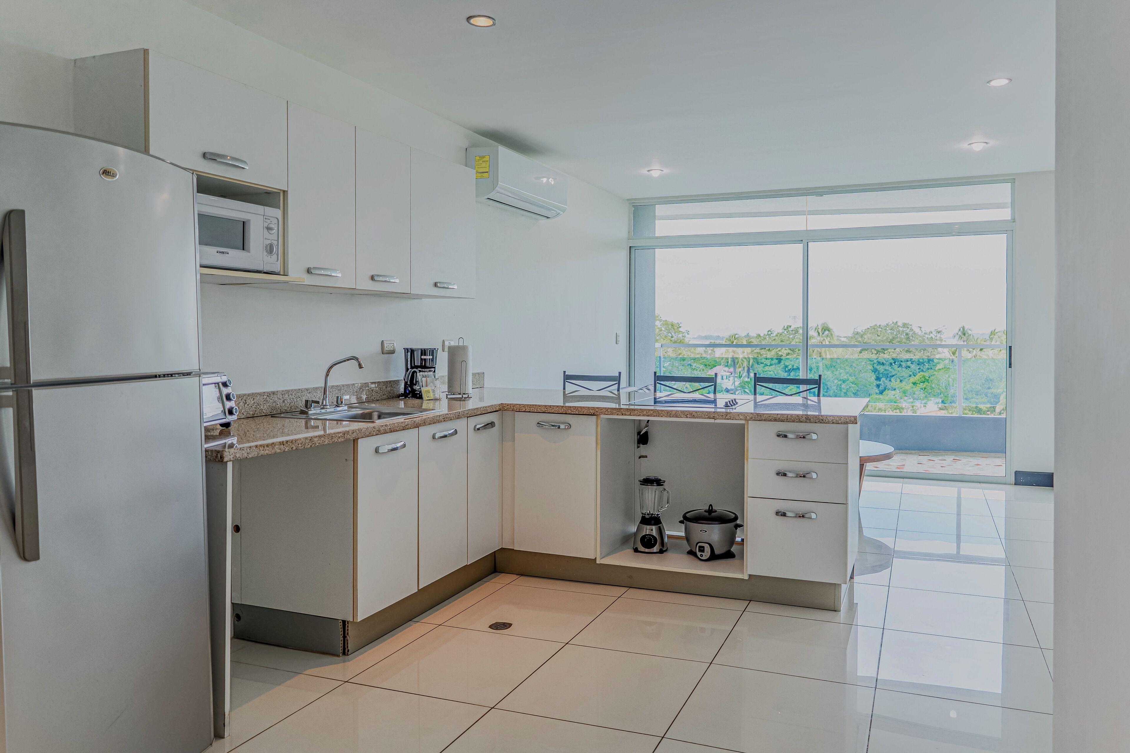 A modern kitchen with a built-in microwave, coffee maker, and a blender on the counter.
