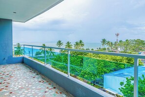 A balcony with a view of the sea and palm trees.